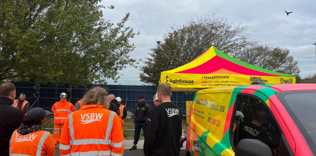 Group of construction workers in hi-vis workwear stood in  a car park