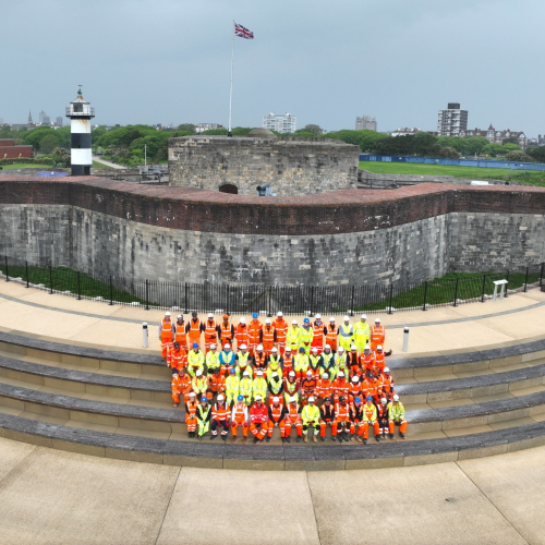 People in highvis sat on the steps of the Southsea Coastal Scheme.