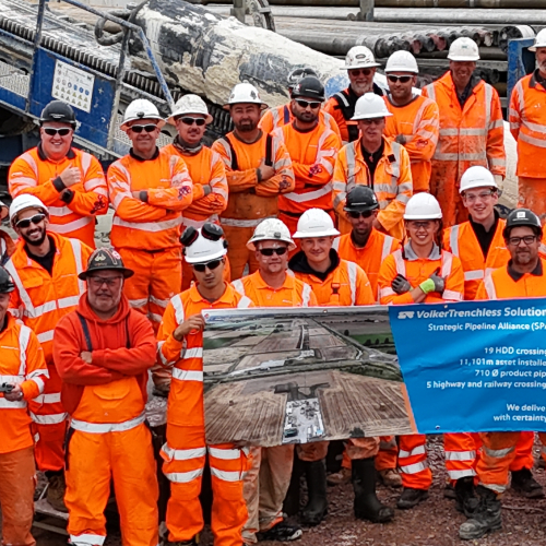 Team photo of people in orange high vis holding a banner.