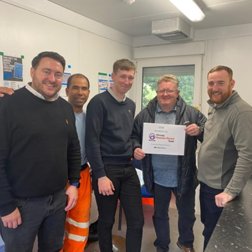 People stood in a kitchen holding a certificate. 