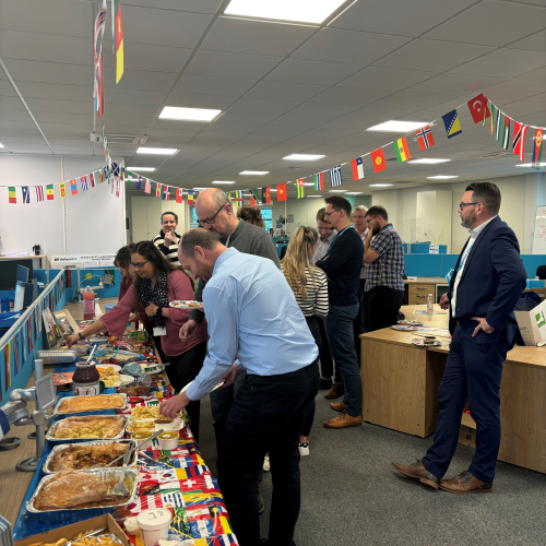 People stood around a buffet table with flags hanging above.