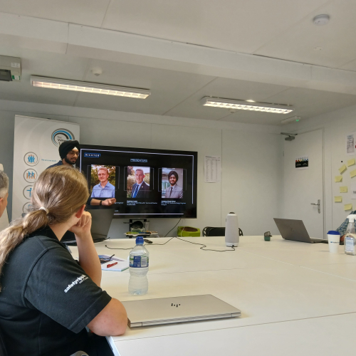 People sat in a room listening to someone talk.