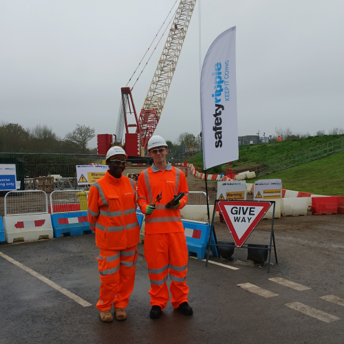 Two men in PPE stood in front of a crane.