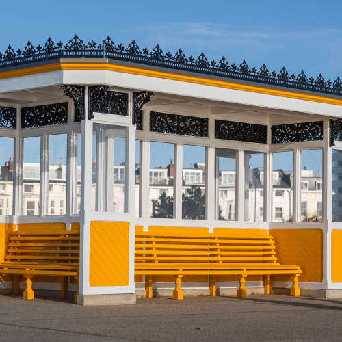 Covered shelter with bench seating around it painted in yellow