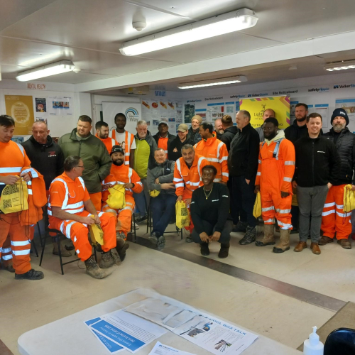 Group of people stood in a huddle, smiling at the camera.