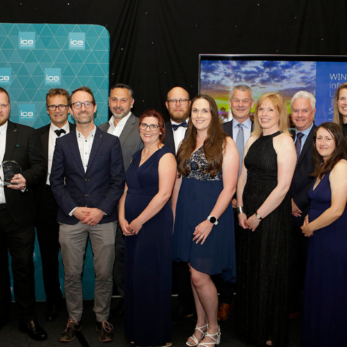 Group photo of men and women in black tie holding a certificate and award