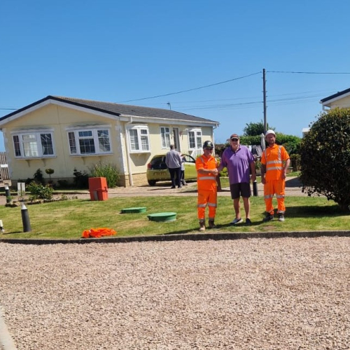 People stood on grass outside a carpark.