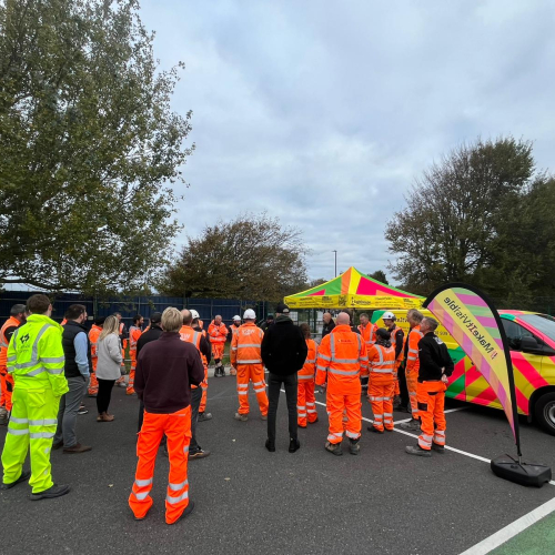 Group of construction workers in hi-vis workwear stood in a group in a car park