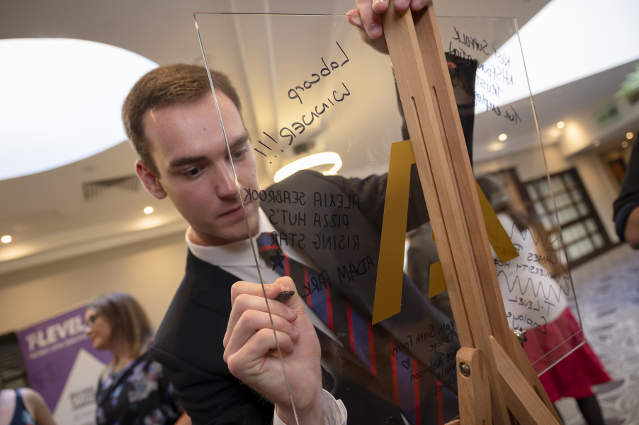 Man writing on a clear Perspex board