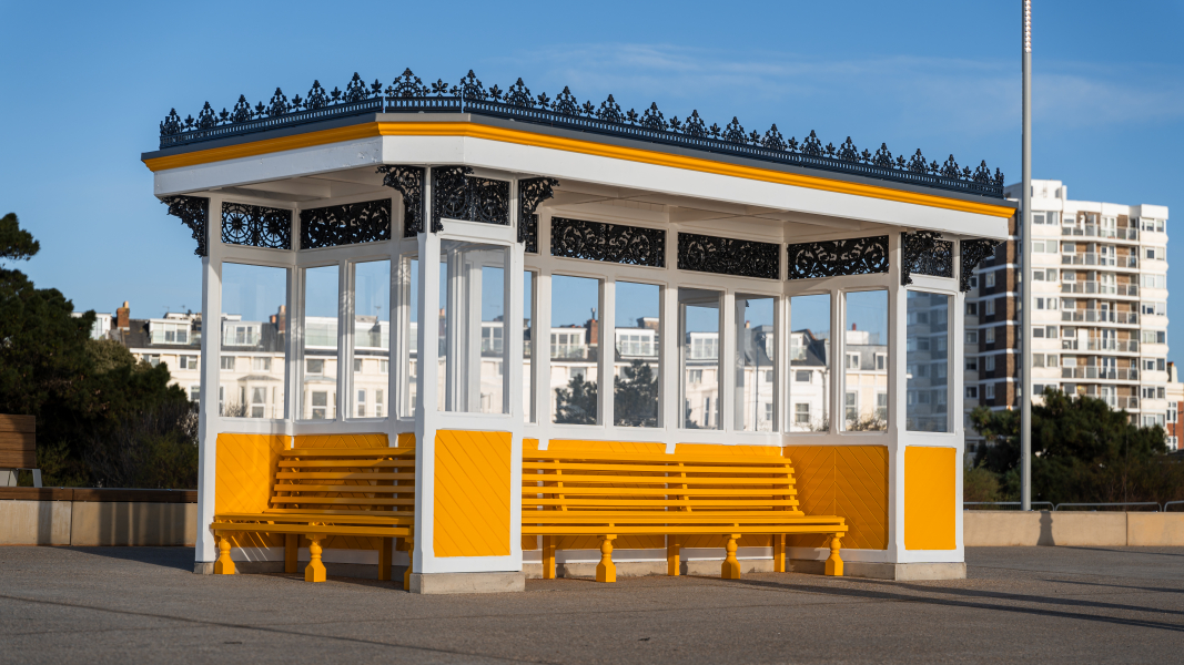 Covered shelter with bench seating around it painted in yellow