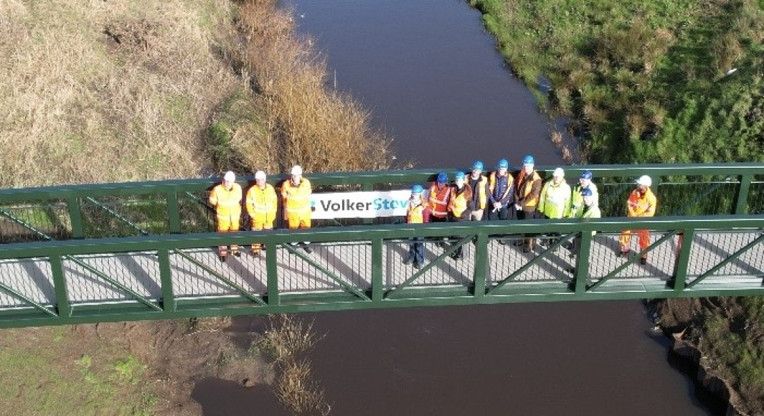 Group of men and women in hi-vis workwear stood on a bridge 