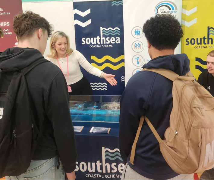 Students stood at a stand watching a wave machine demonstration