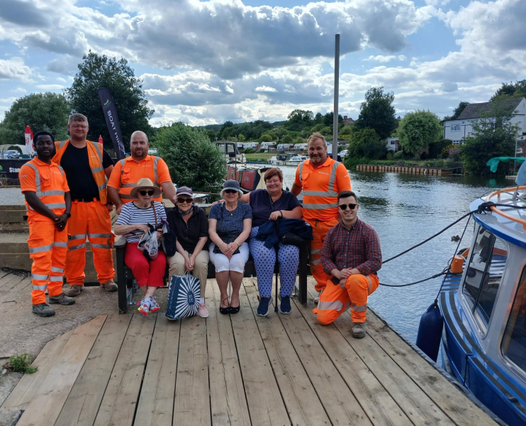 A group of men and women with construction workers sat by a river