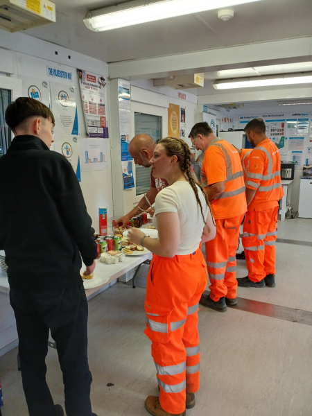 Men and women in orange hi-vis workwear at a buffet table