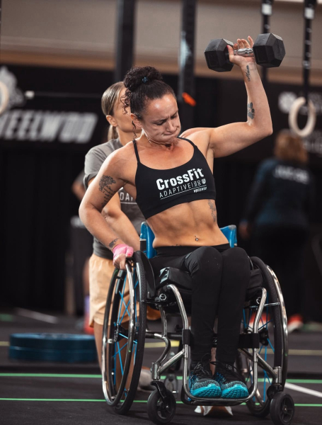 Women in a wheelchair in a gym lifting a dumbell