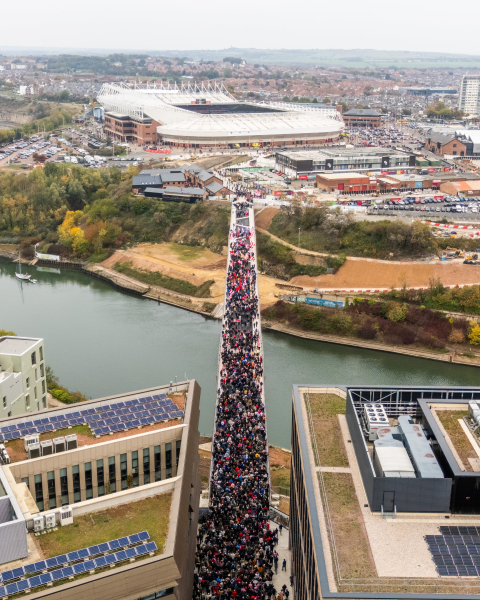 Keel Crossing opening - aerial image of a large group of people walking across the bridge
