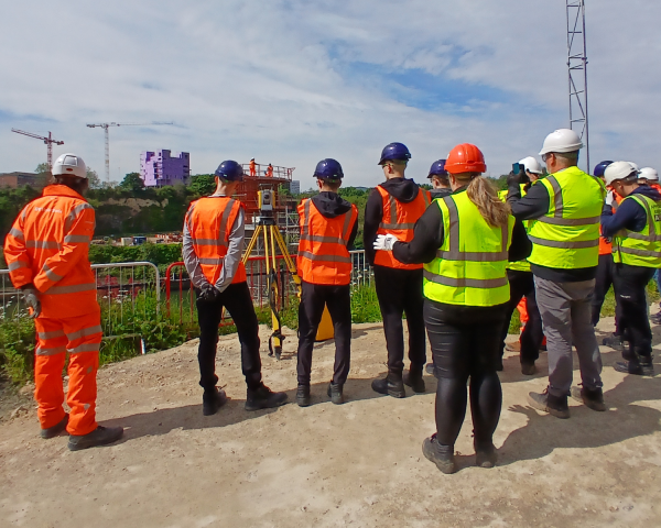 People in highvis on a site tour of the New Wear high-level Footbridge sign.