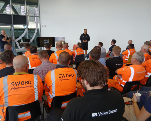 People in highvis watching a presentation. 