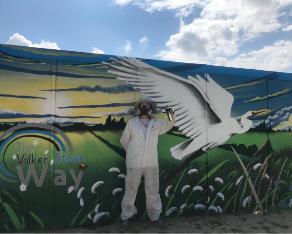 Picture of artist stood in front of the mural.
