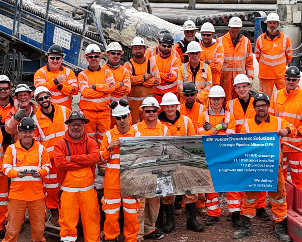Team photo of people in orange high vis holding a banner.