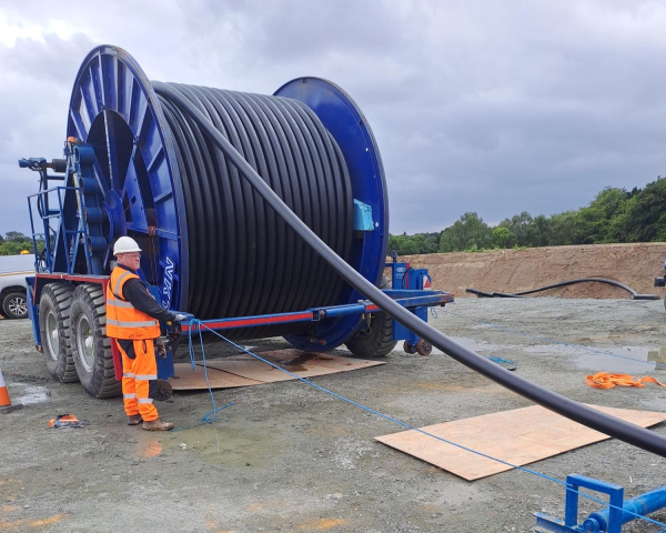 Cable drum with man feeding the cable of it. 