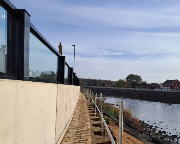 Wall with glass panels on the top alongside a river