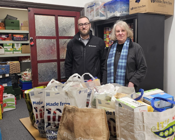 Man and women stood by table with food donations