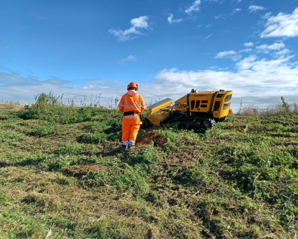 Picture of a man stood next to a digital lawnmower.