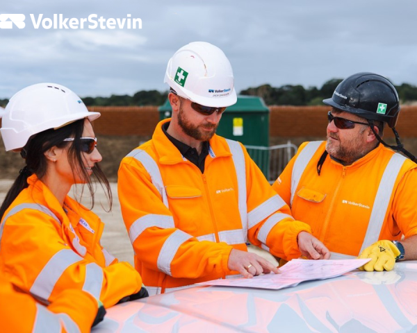 Three people looking at a book smiling