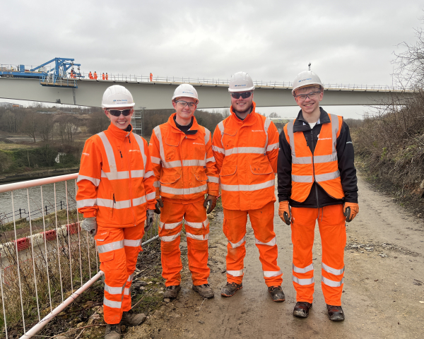 Four people stood in front of a bridge.