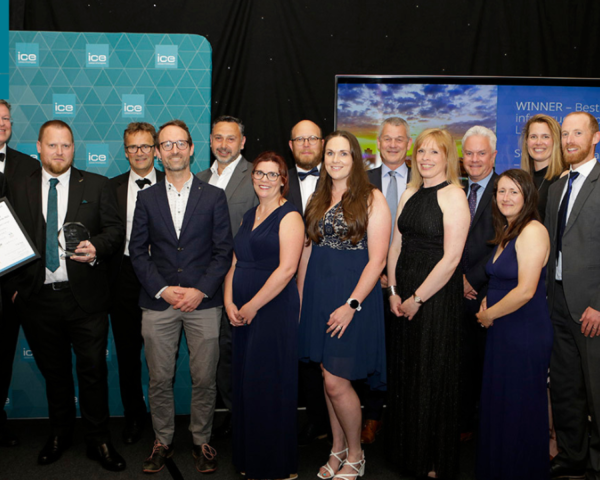 Group photo of men and women in black tie holding a certificate and award
