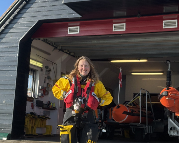 Girl in an RNLI kit outside a boat centre.