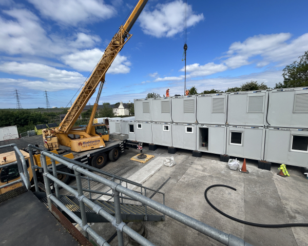 a crane putting into place double stacked accommodation units on a construction site