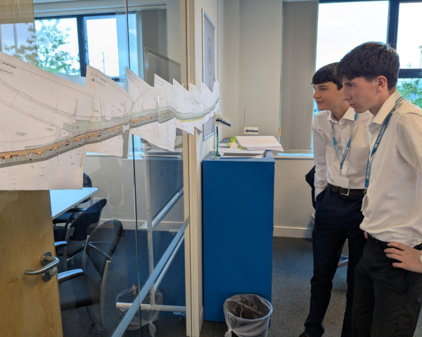 Two buys in white shirts looking at construction drawings