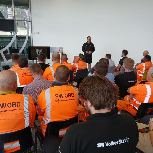 People in highvis watching a presentation. 