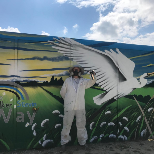 Picture of artist stood in front of the mural.