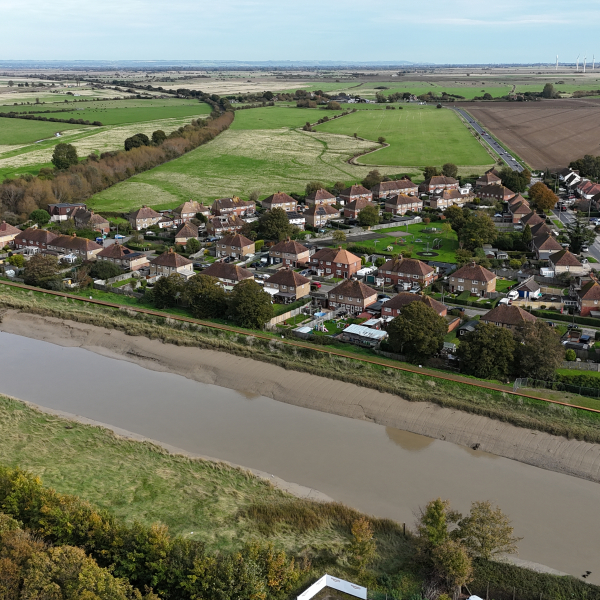 Picture of a river running in front of houses. Rother Tidal Walls 