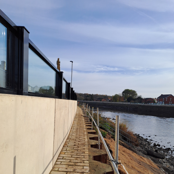 Wall with glass panels on the top alongside a river