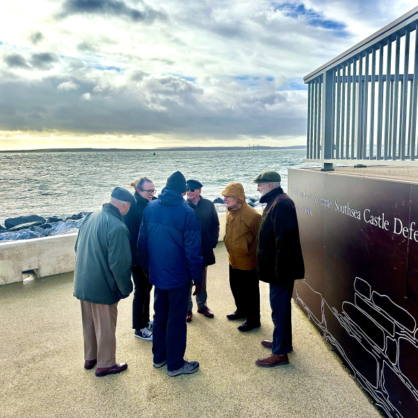 A group of male retired engineers stood by fencing on Southsea promenade