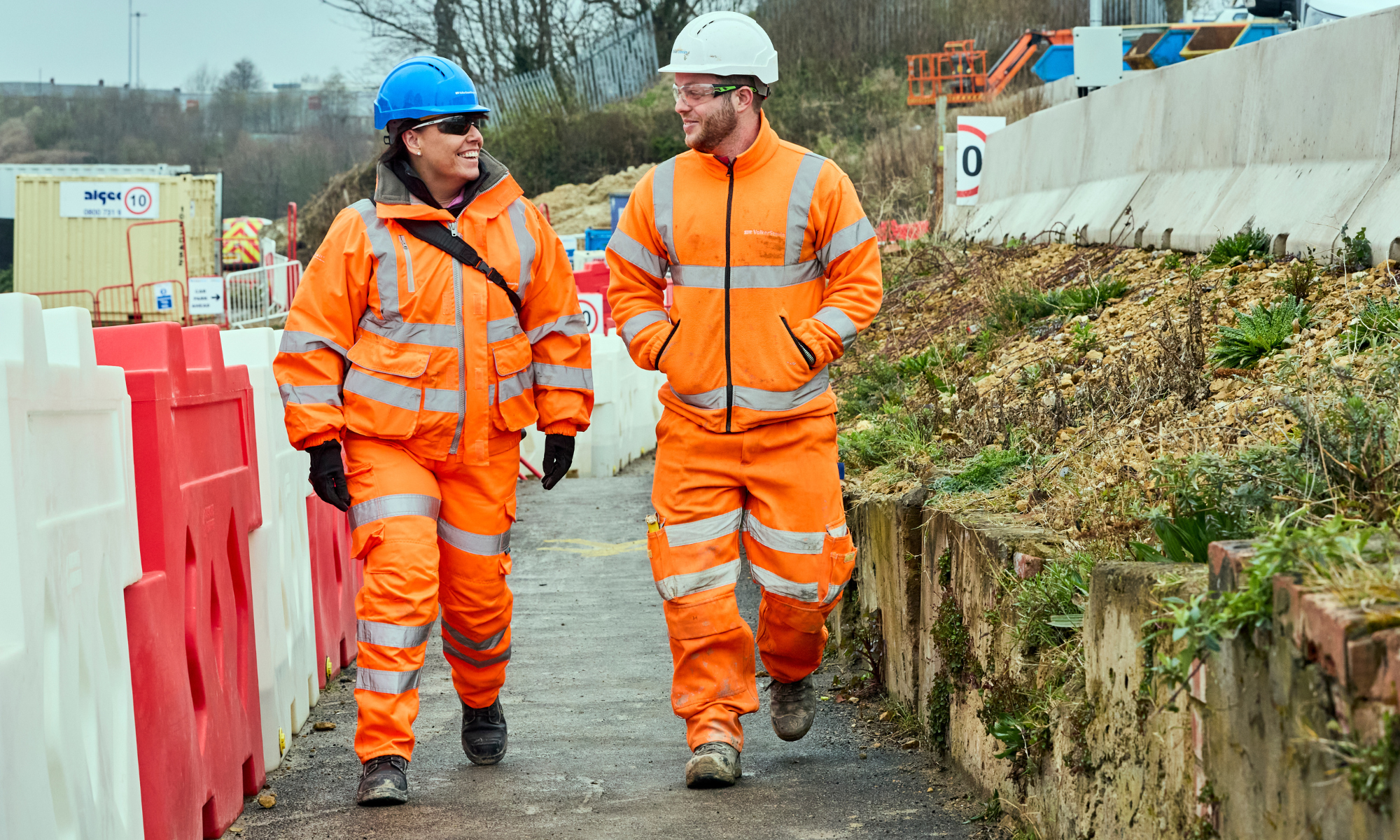 Picture of two VolkerStevin employees in orange high vis on site.